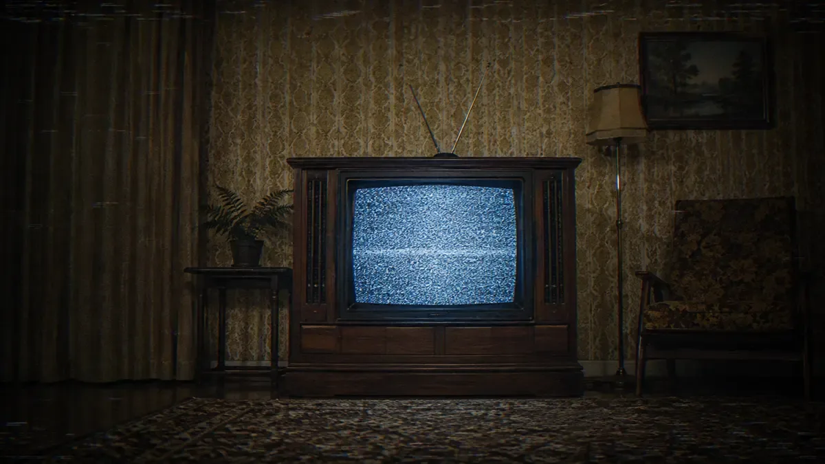 Televisor de mueble de madera con antena de conejo encendido en estática en una sala antigua