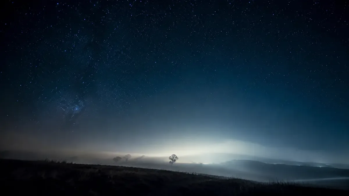 Cielo nocturno con una luz difusa inexplicable y niebla baja